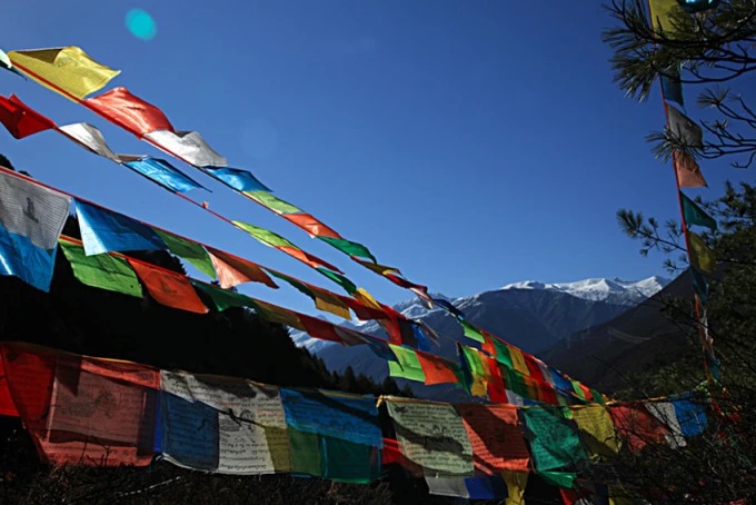 Five-colour prayer flags strung across a highland landscape