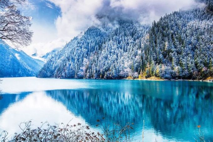 Schneebedecktes Tal von Jiuzhaigou mit dunklem Wald und blassem Winterlicht