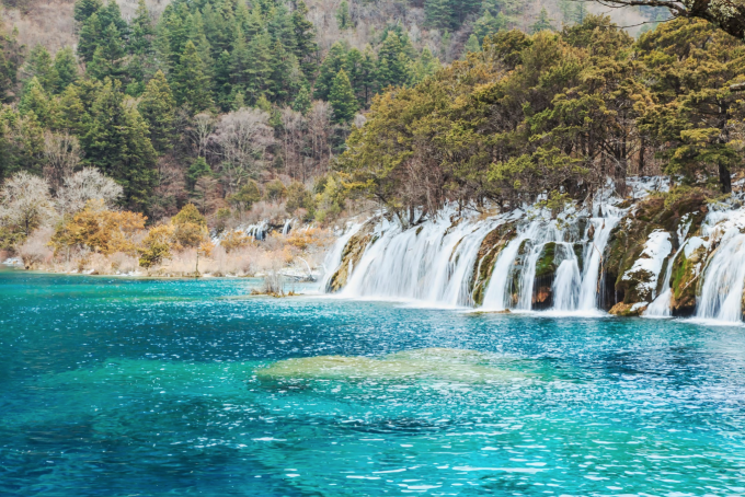 Waldbedeckte Hänge, die sich in Jiuzhaigou im Wasser spiegeln