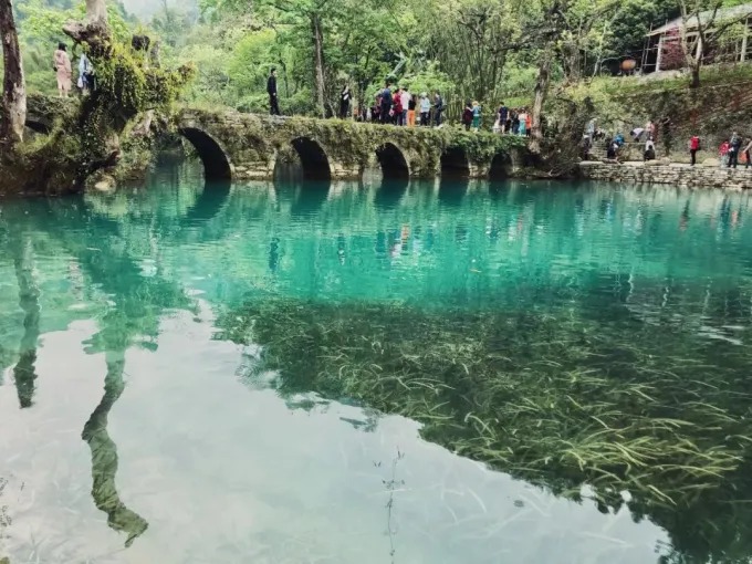 Puente de piedra de siete arcos sobre aguas verdes en Xiaoqikong