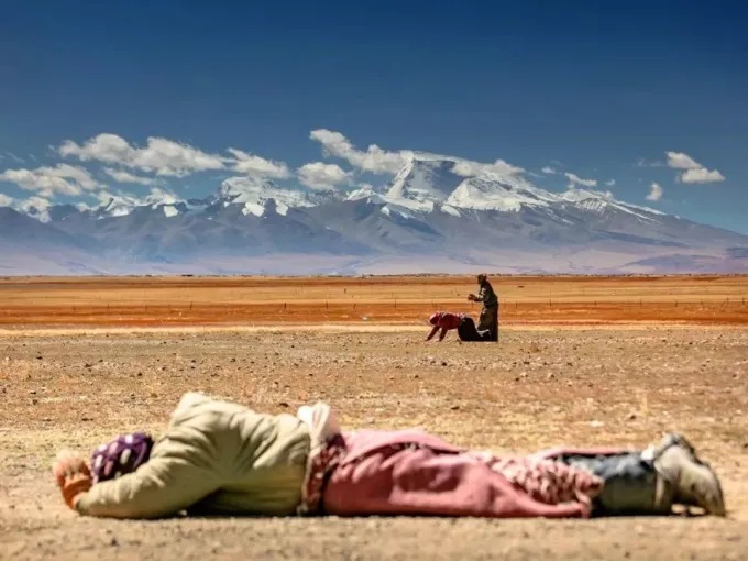 A road crossing a high-altitude desert beneath broken light