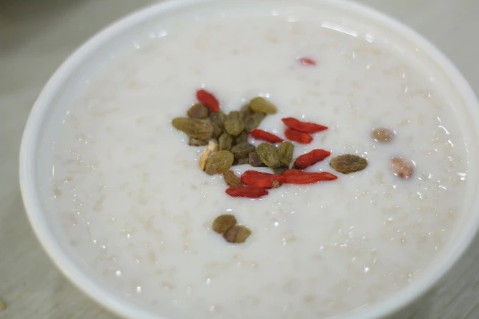 Un cuenco de gachas de leche con semillas de loto, bayas de goji y frutos secos