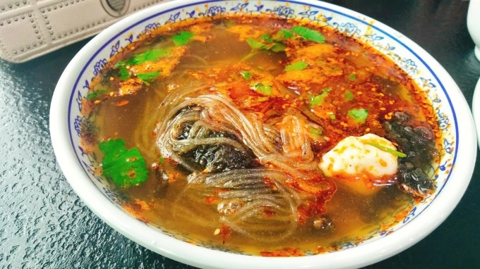 Un cuenco de sopa agria con empanadillas y fideos de fécula