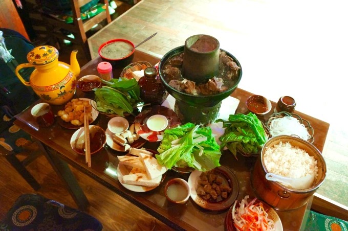 A shared hotpot meal with vegetables, rice, small dishes and tea
