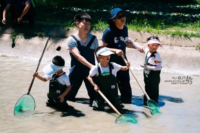 烏村の池で防水服を着て魚を捕る子どもたち