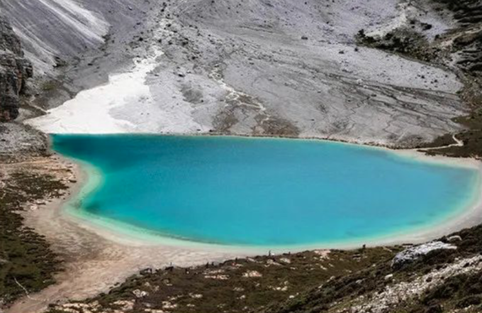 Lago de Leche bajo las laderas rocosas claras de Yading
