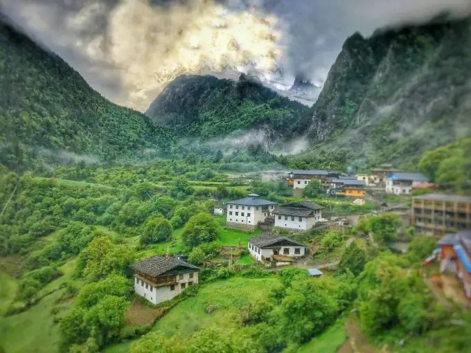Yubeng zwischen grünen Hängen unter den Bergen