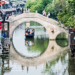 A sightseeing boat passing beneath a stone bridge in Zhouzhuang